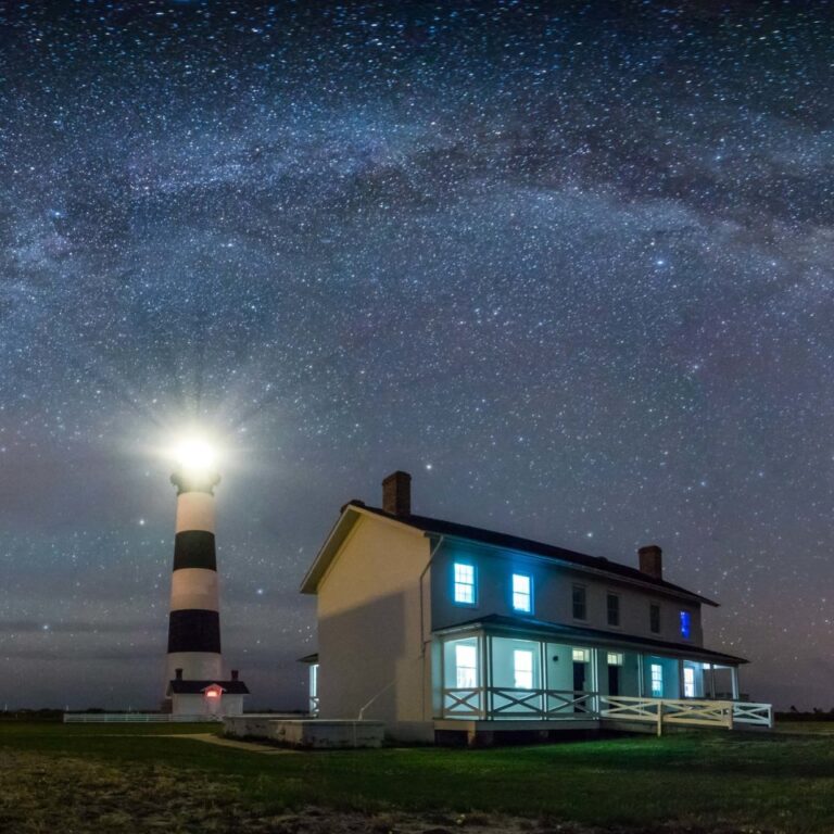 A lighthouse at night with Milky Way above